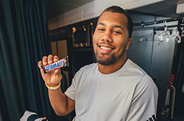 1UP Sports Marketing client Bradley Chubb holding a Snickers