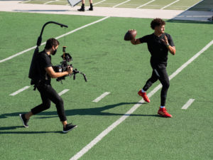 1UP Sports Marketing client Patrick Mahomes about to throw a football and being filmed by a videographer