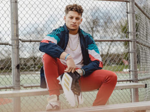 1UP Sports Marketing client Patrick Mahomes sitting on bench holding his adidas shoes