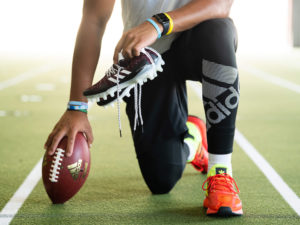 1UP Sports Marketing client Patrick Mahomes kneeling with a football and adidas shoes