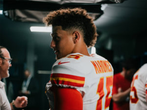 Side shot of 1UP Sports Marketing client Patrick Mahomes in a locker room wearing his jersey