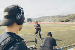 1UP Sports Marketing client Patrick Mahomes prepares to throw the football while being videotaped for a TV commercial