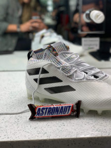 Snickers bar labeled with "Astronaut" leaning up against shoes owned by 1UP Sports Marketing client Bradley Chubb