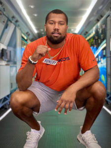 1UP Sports Marketing client Bradley Chubb kneels with a Snickers "Hungry" chain and pendant